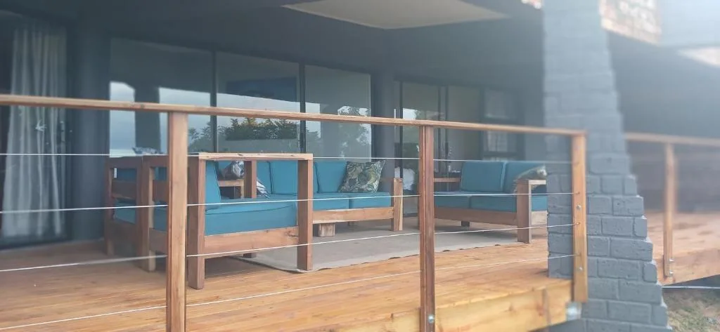Wooden deck with blue cushioned seating and metal railings overlooking property