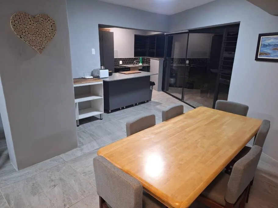 Open-plan dining area with wooden table and kitchen visible beyond