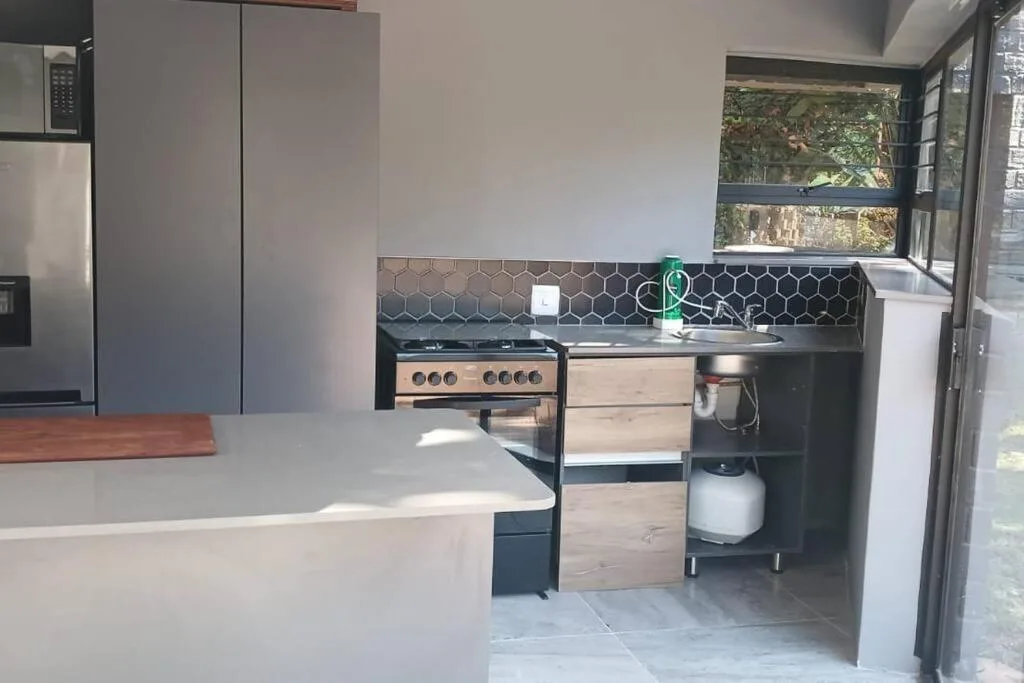 Modern kitchen with hexagonal backtile, gas range, and sliding doors to garden