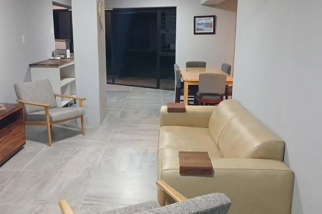 Open-plan lounge with cream sofa, armchair, and dining area visible