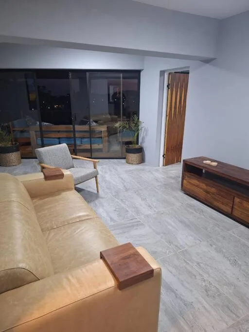 Modern lounge with cream sofa, wooden furniture, and evening views