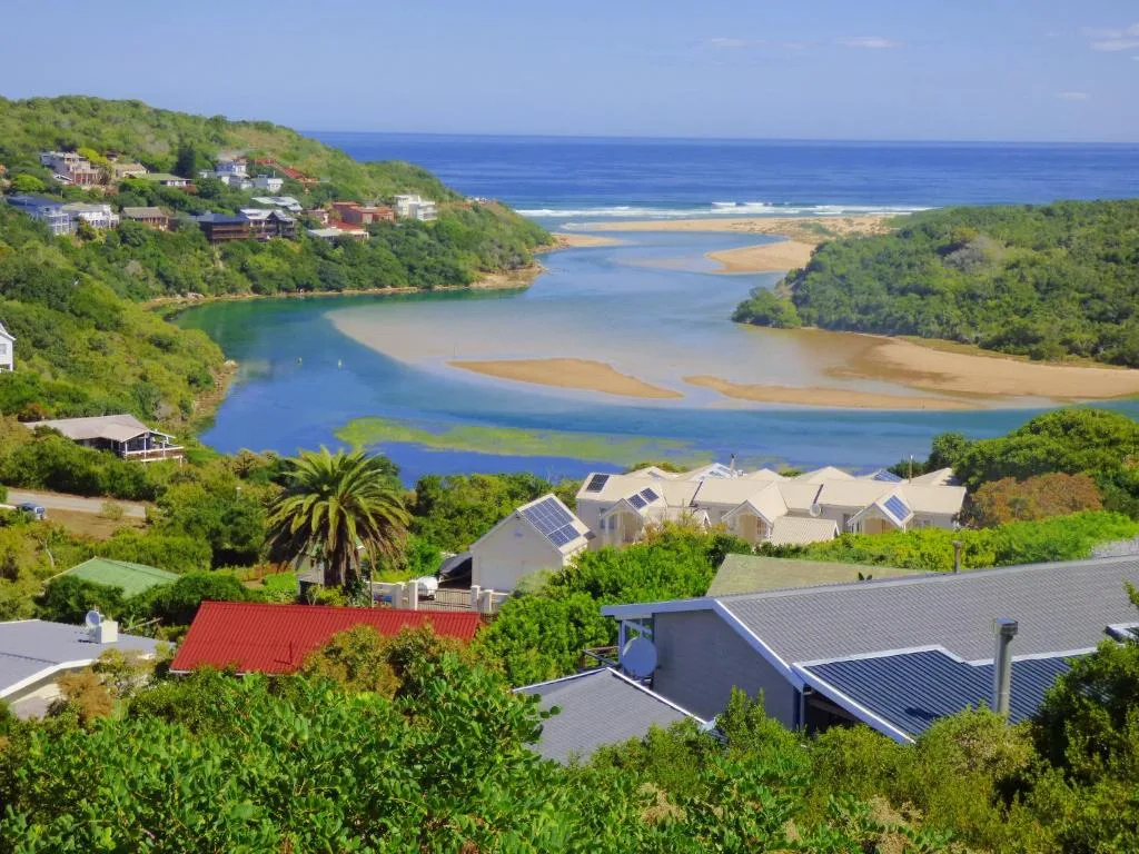 Scenic lagoon and ocean vista with coastal homes nestled in lush hills