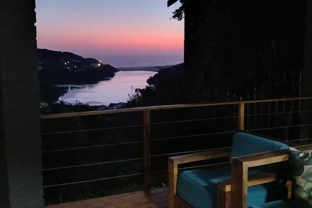 Sunset over lagoon with coastal hills and deck seating foreground