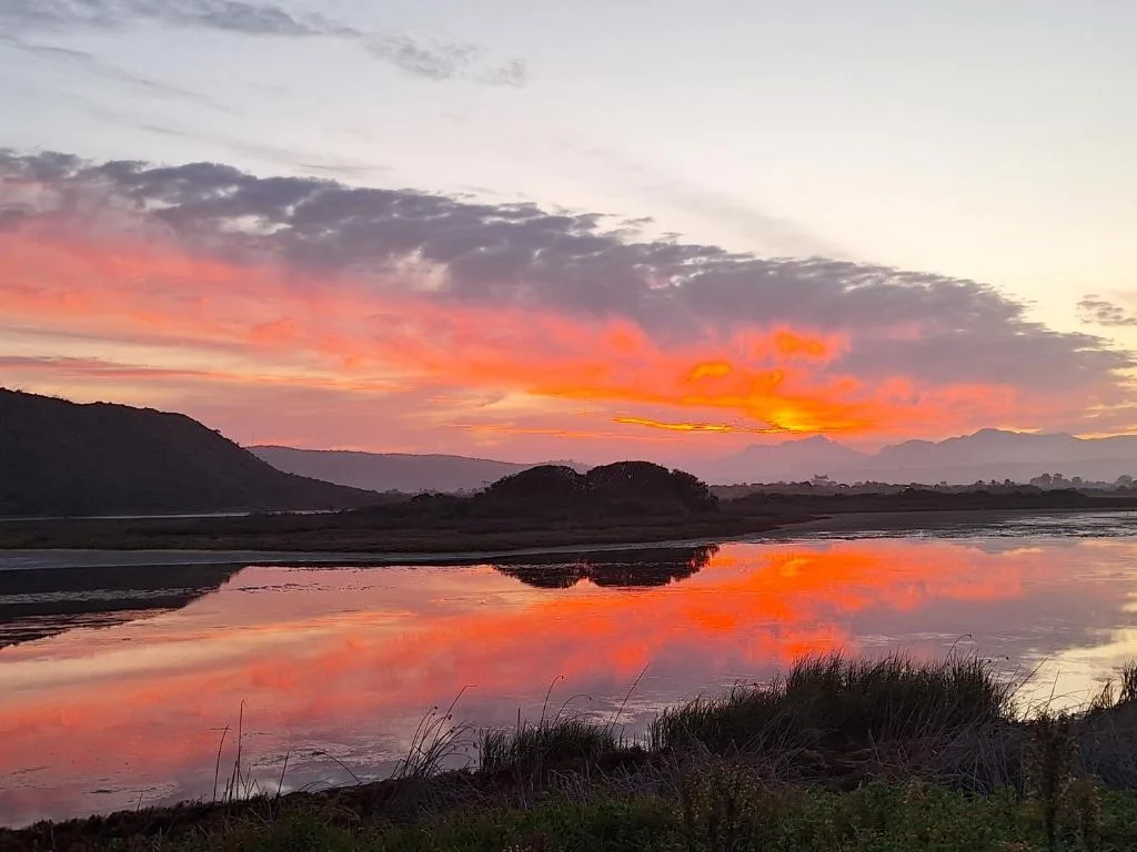 Stunning sunset reflected in lagoon with mountains silhouetted