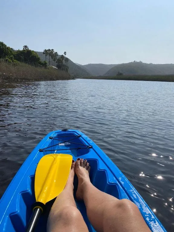 Kayaking on calm lagoon with lush mountains and palm trees in distance