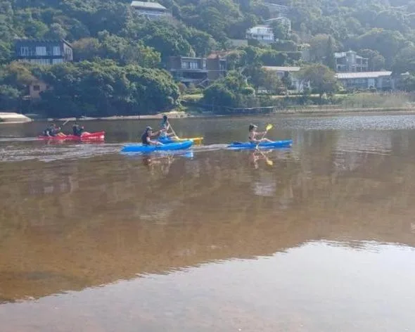 Lagoon view with kayakers and tree-lined residential hillside