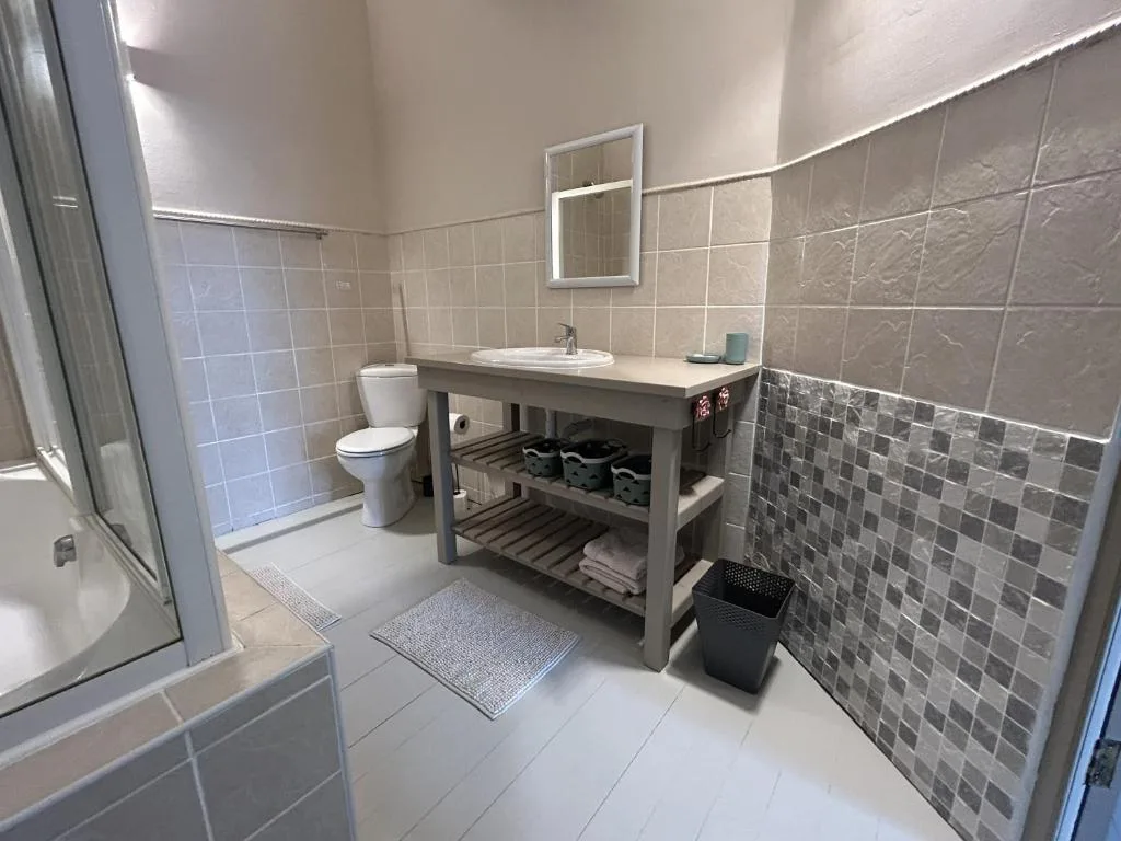 Modern bathroom with vanity sink, toilet, and shower enclosure with gray tile