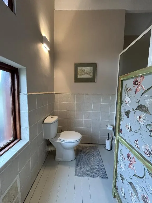 Compact bathroom with toilet, small sink, and tiled walls near window