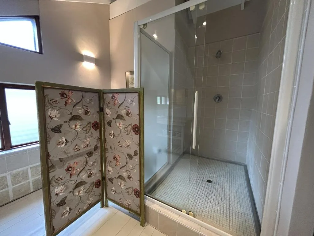 Modern bathroom with walk-in shower, glass enclosure, and decorative folding screen