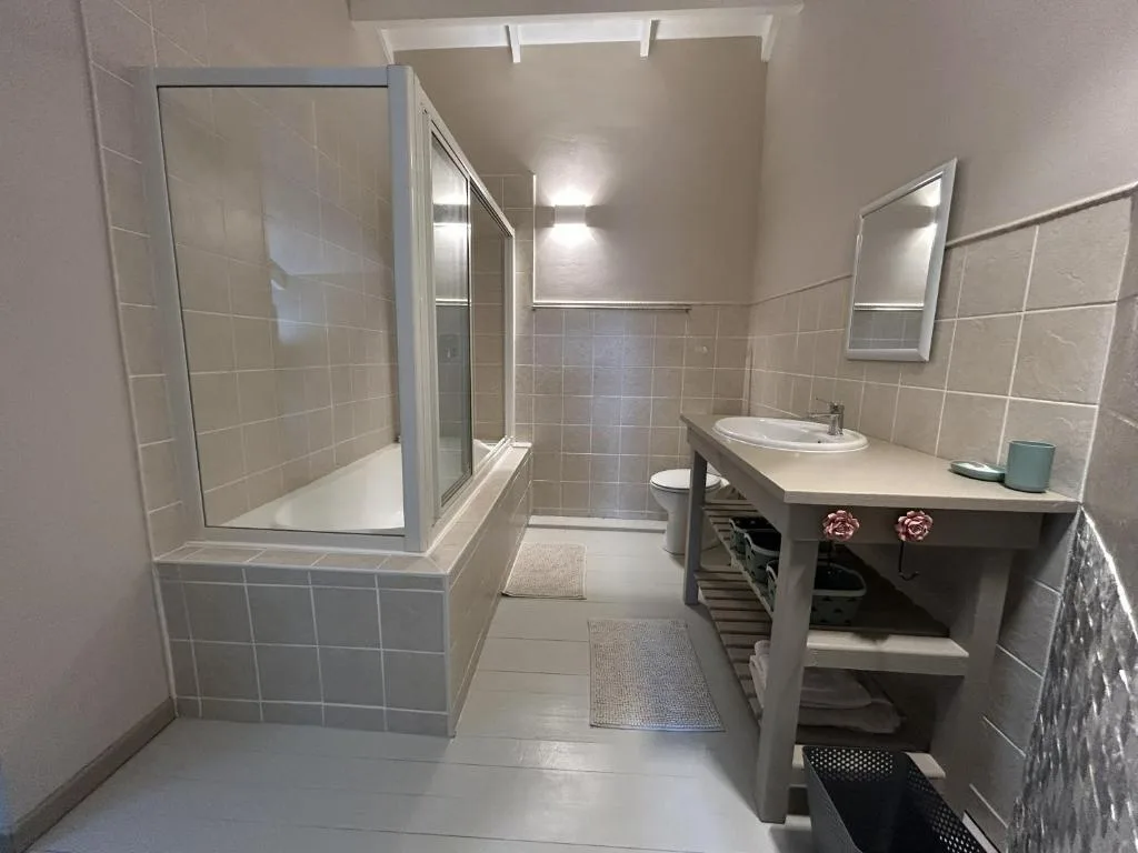 Spacious bathroom with shower enclosure, vanity sink, and tiled walls