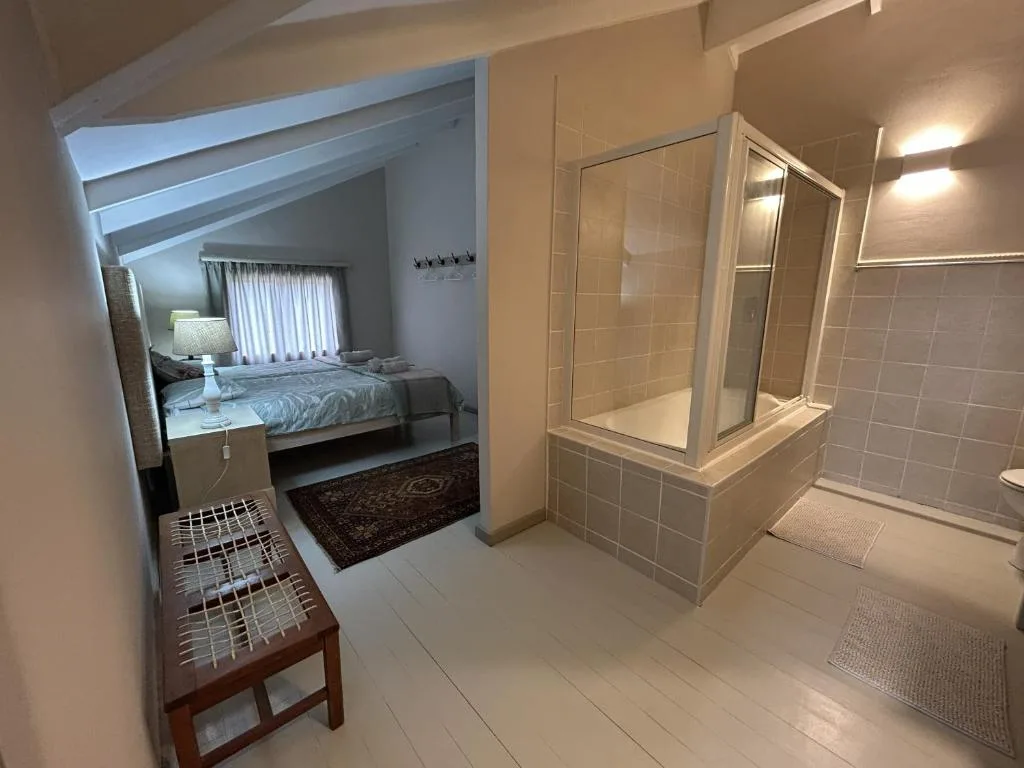 Bedroom with ensuite bathroom featuring shower enclosure and vanity mirror