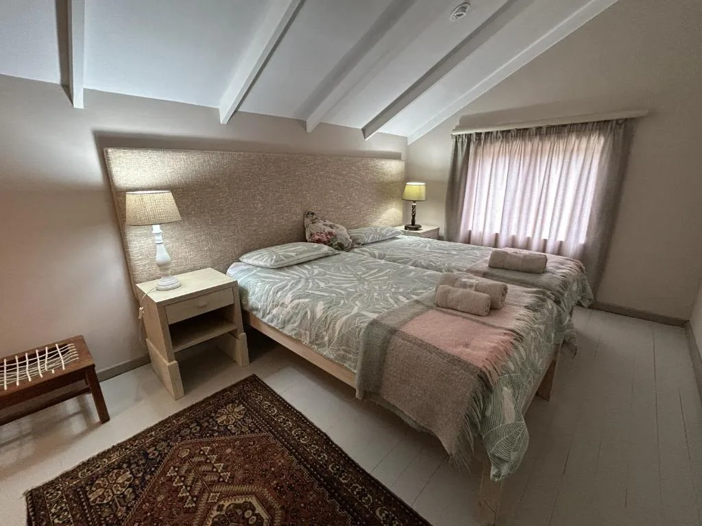 Bright bedroom with twin beds, textured headboard, and natural light