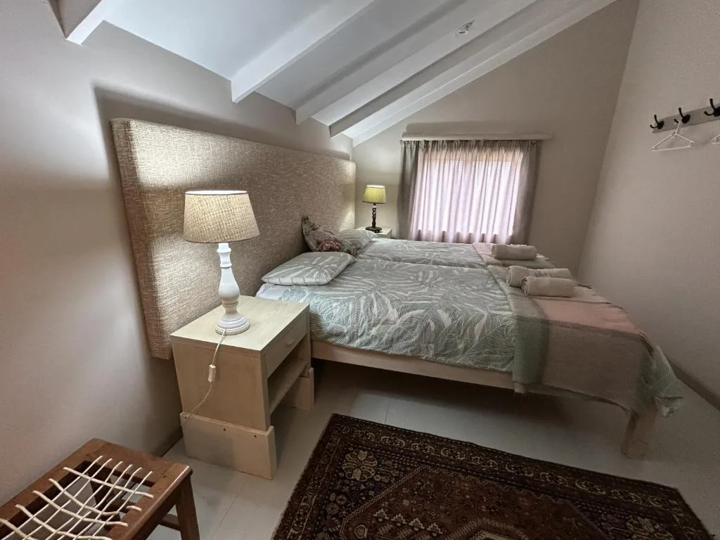 Bright bedroom with queen bed, textured headboard, bedside lamp, and natural light