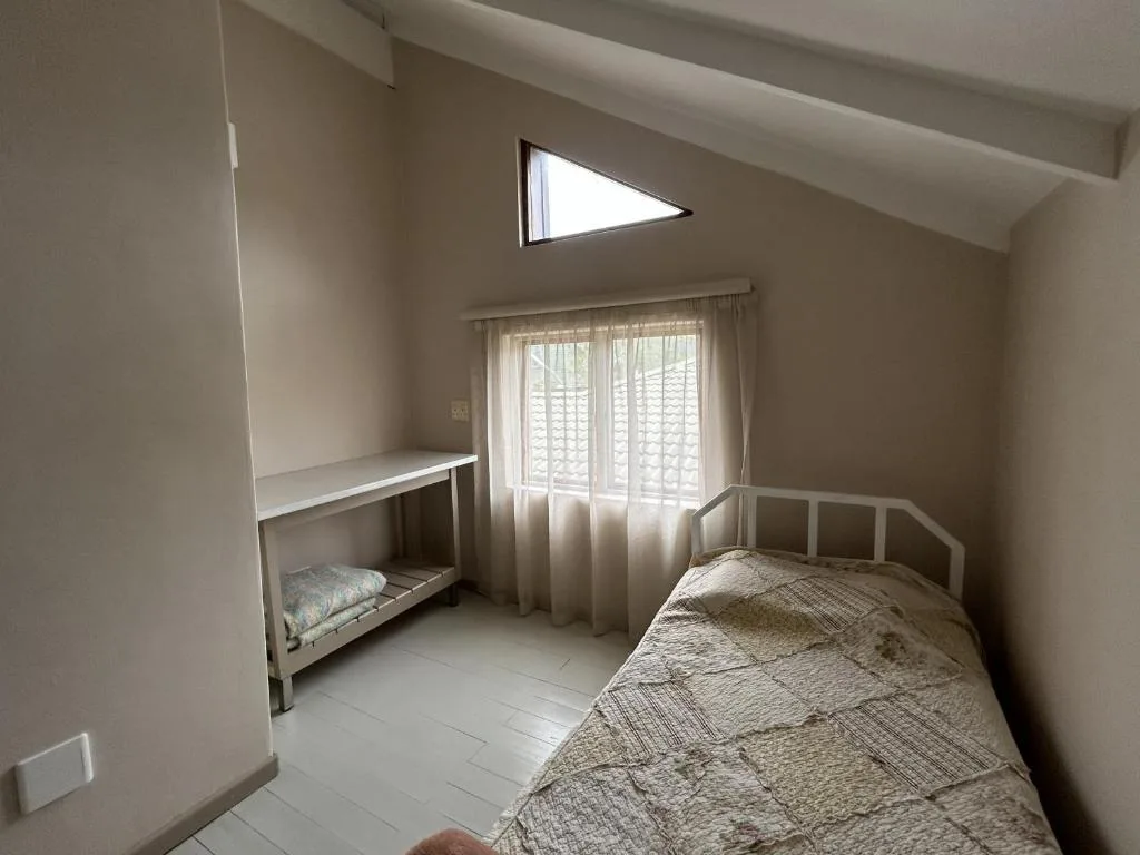 Bright bedroom with single bed, bunk bed, and natural light from windows