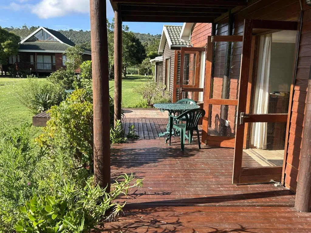 Wooden deck with outdoor seating, garden views, and cottage entrance