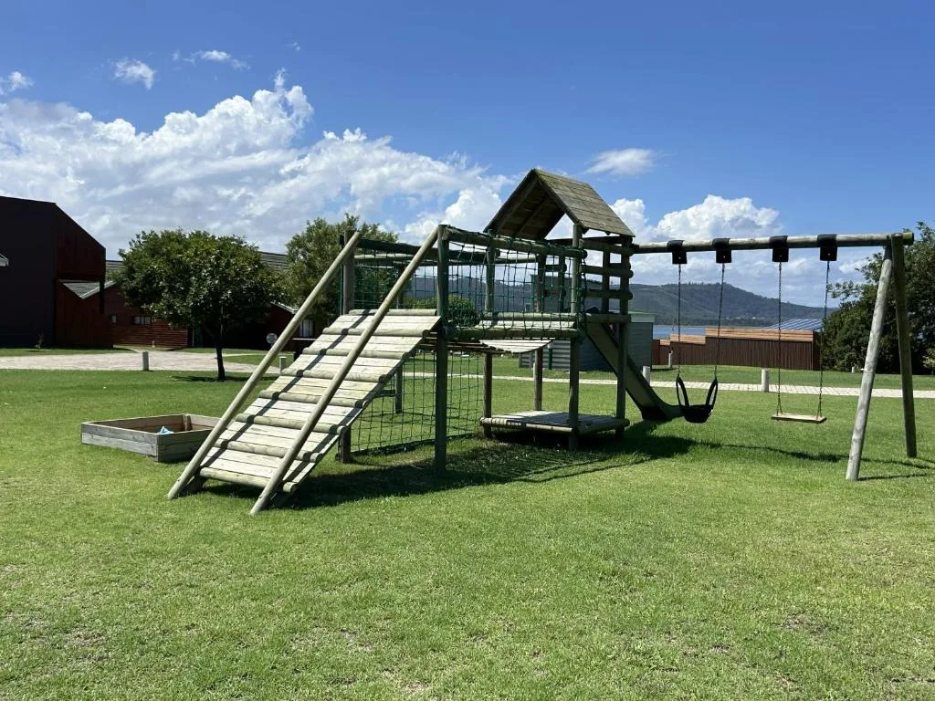 Children's playground with slide, swings, and climbing structure on manicured lawn
