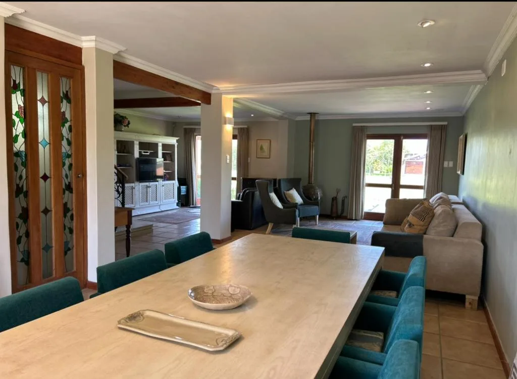 Open-plan dining area with wooden table and teal upholstered chairs