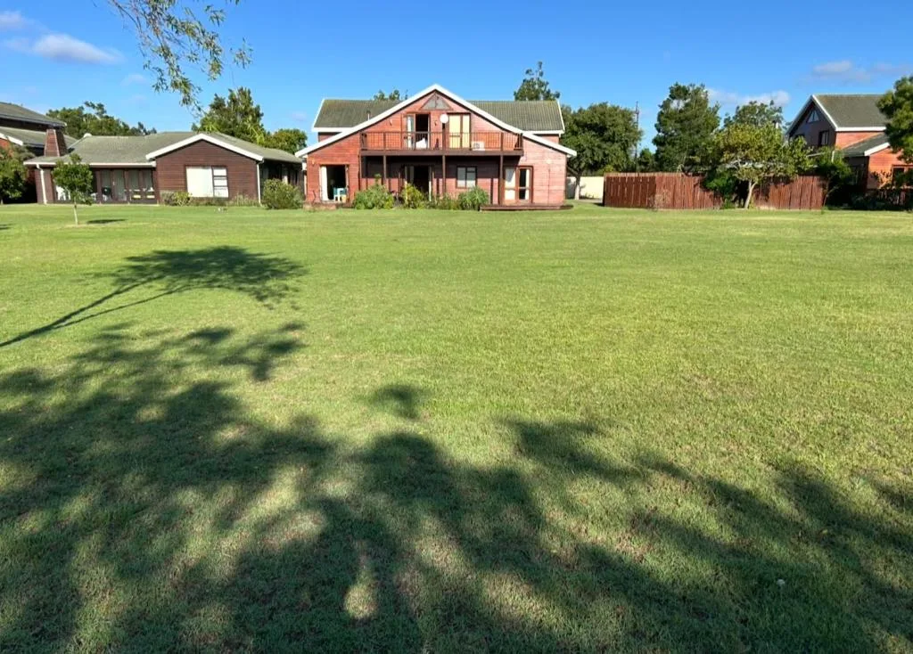 Red brick cottage with large lawn and surrounding properties in estate