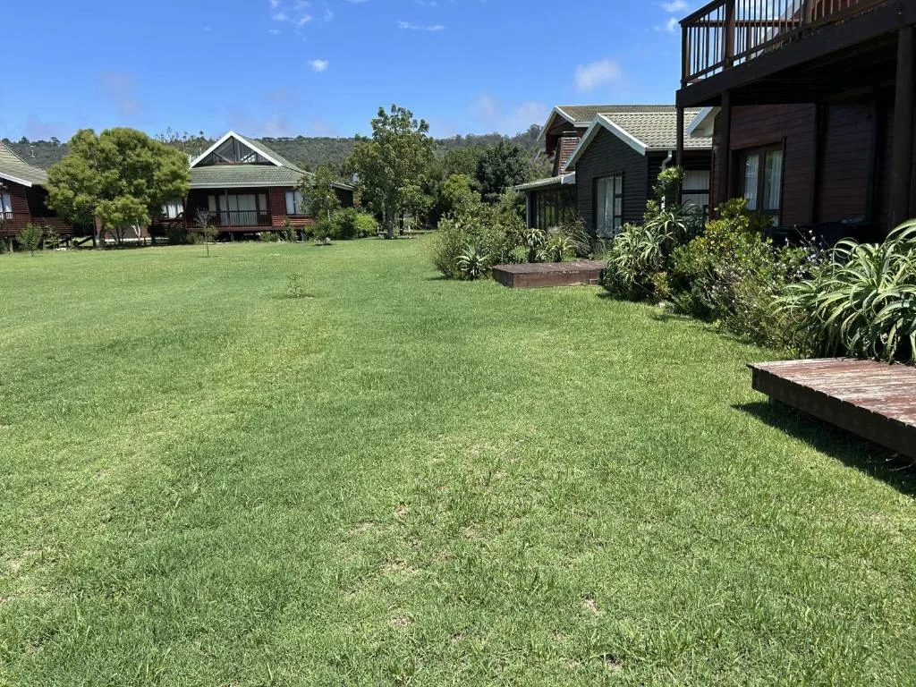 Spacious green lawn with modern cottage buildings and mountain backdrop