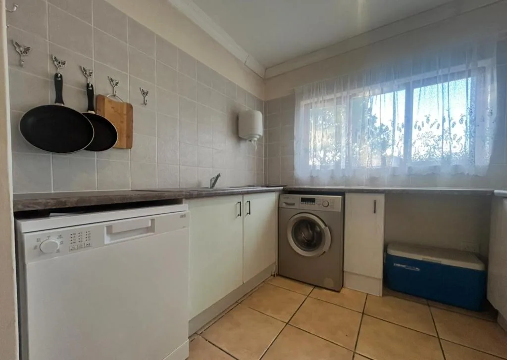 Bright kitchen with white cabinetry, dishwasher, washing machine, and natural light