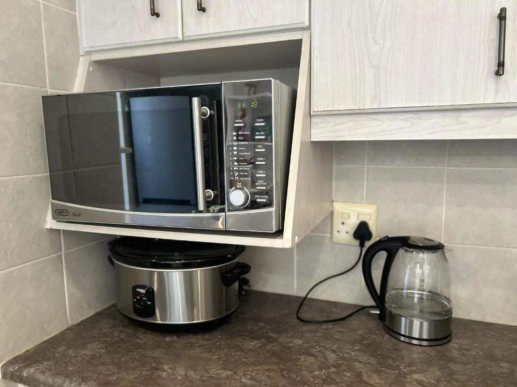 Kitchen counter with microwave, slow cooker, and electric kettle appliances