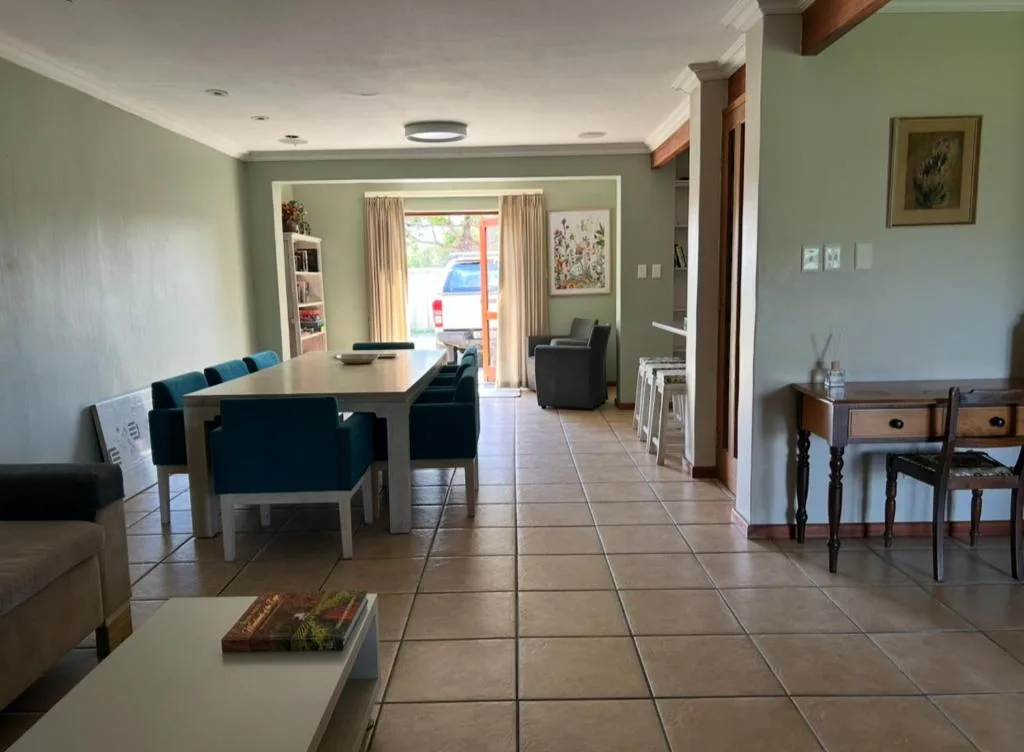 Open-plan lounge and dining area with sage green walls and tile flooring