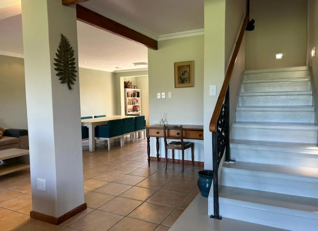 Open-plan lounge with dining area, wooden beams, and staircase access