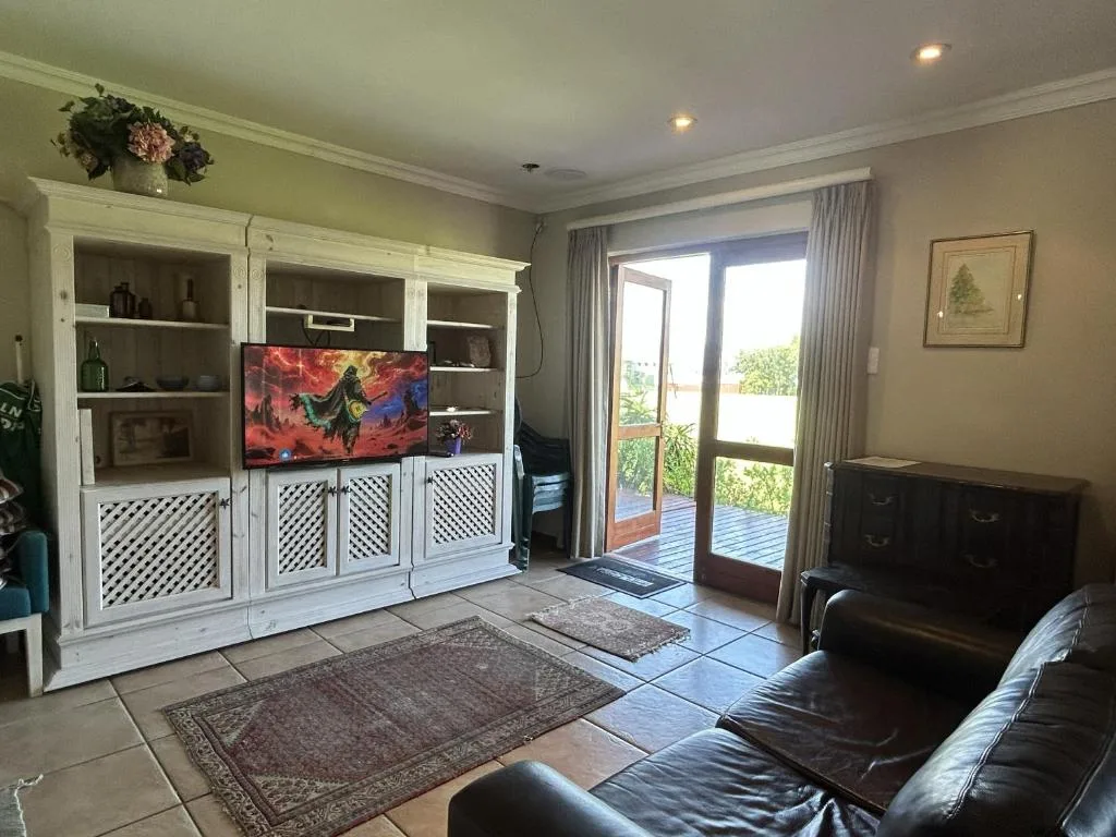 Modern living room with black leather seating and white built-in entertainment unit