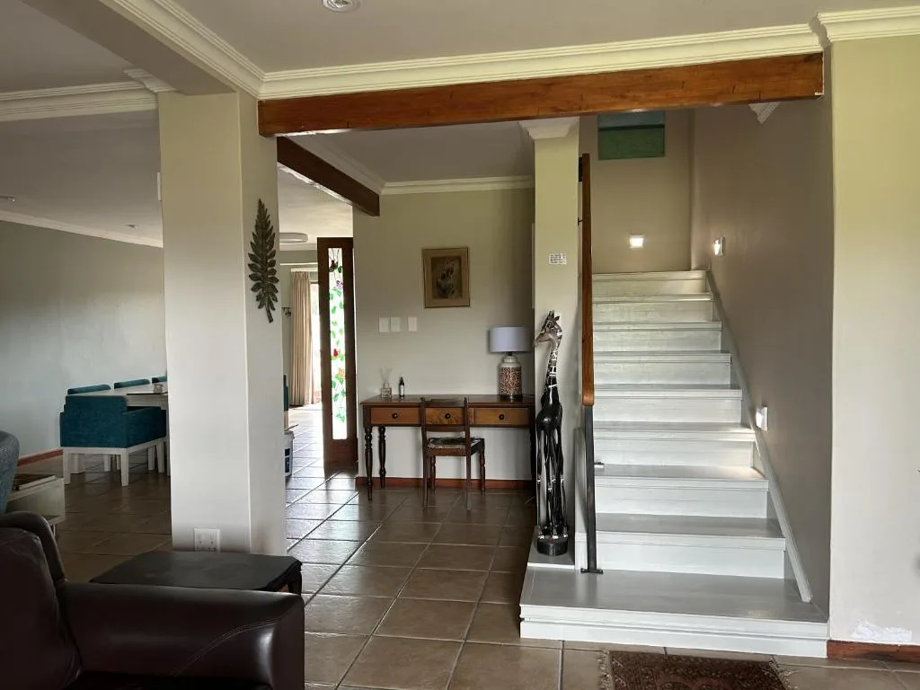 Open-plan lounge with staircase, wooden beams, and neutral decor