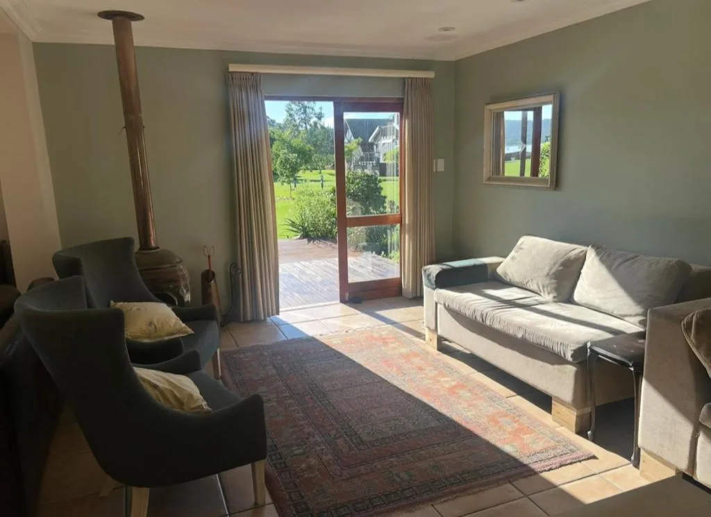 Spacious lounge with comfortable seating and wood stove, opening to garden deck