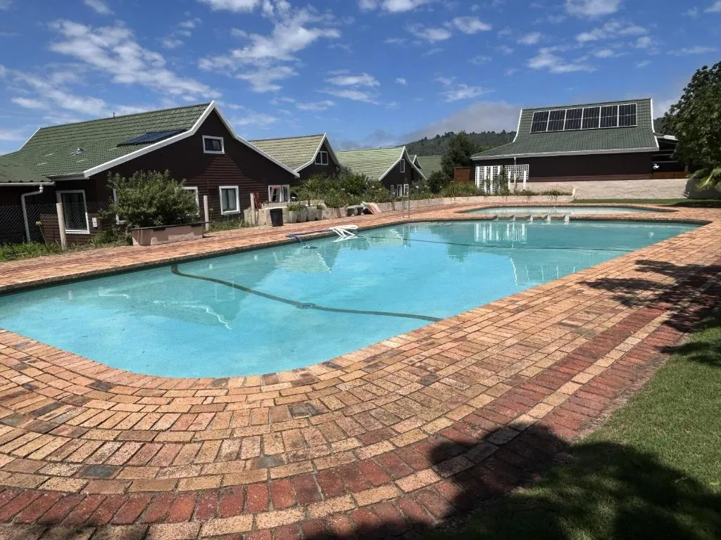 Sparkling blue swimming pool with brick patio and cottage buildings