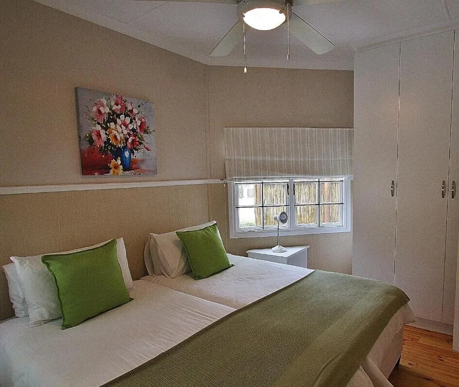 Spacious bedroom with queen bed, green accents, and floral wall art