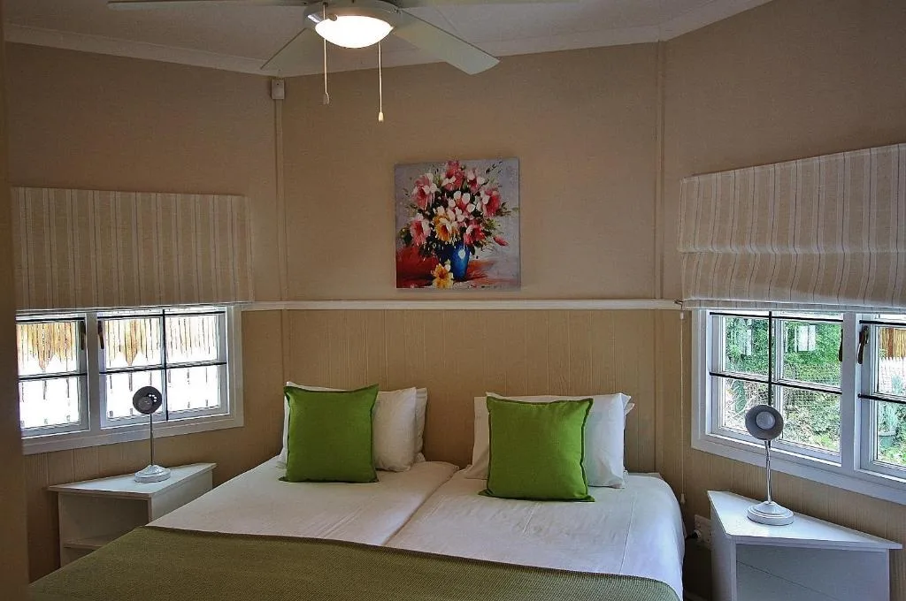 Bright bedroom with queen bed, green accent pillows, and garden views through windows