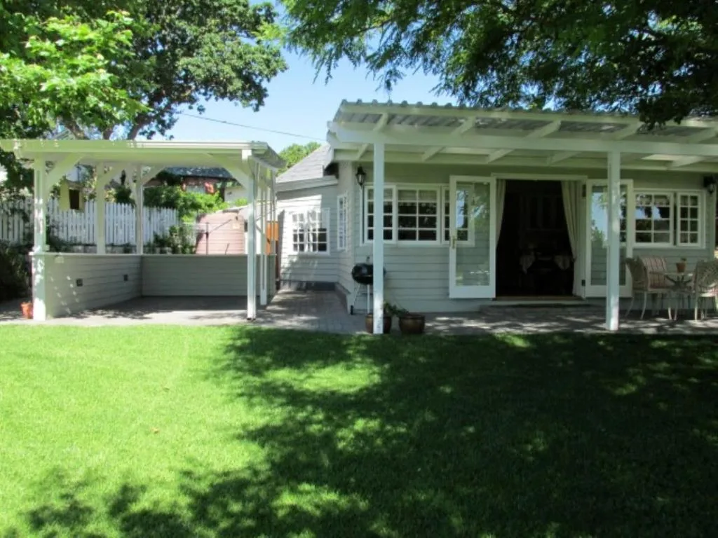 Modern cottage with white pergola deck and manicured lawn area