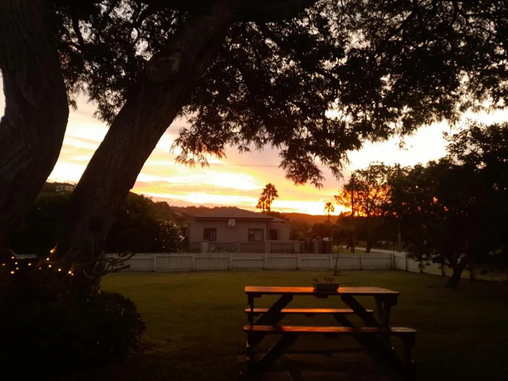 Golden sunset over garden with picnic table and colonial homestead