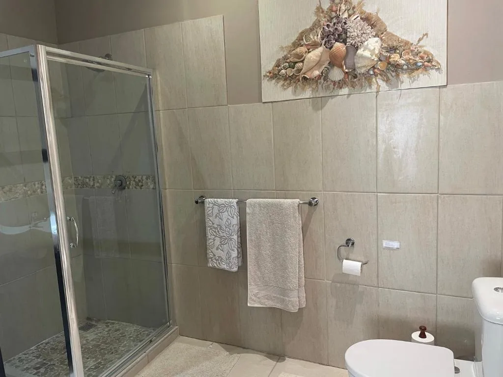 Modern bathroom with shower enclosure, beige tiles, and coastal decor