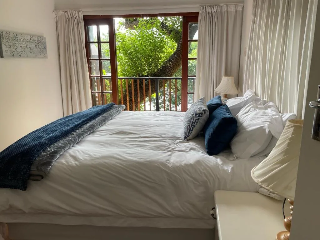 Bright bedroom with queen bed, garden views through wooden doors