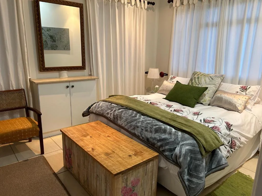 Bright bedroom with queen bed, green accents, and natural light from windows