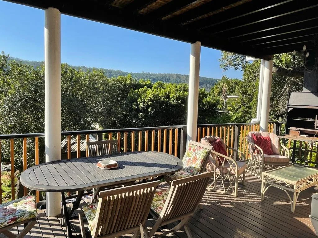 Covered wooden deck with dining table and mountain views