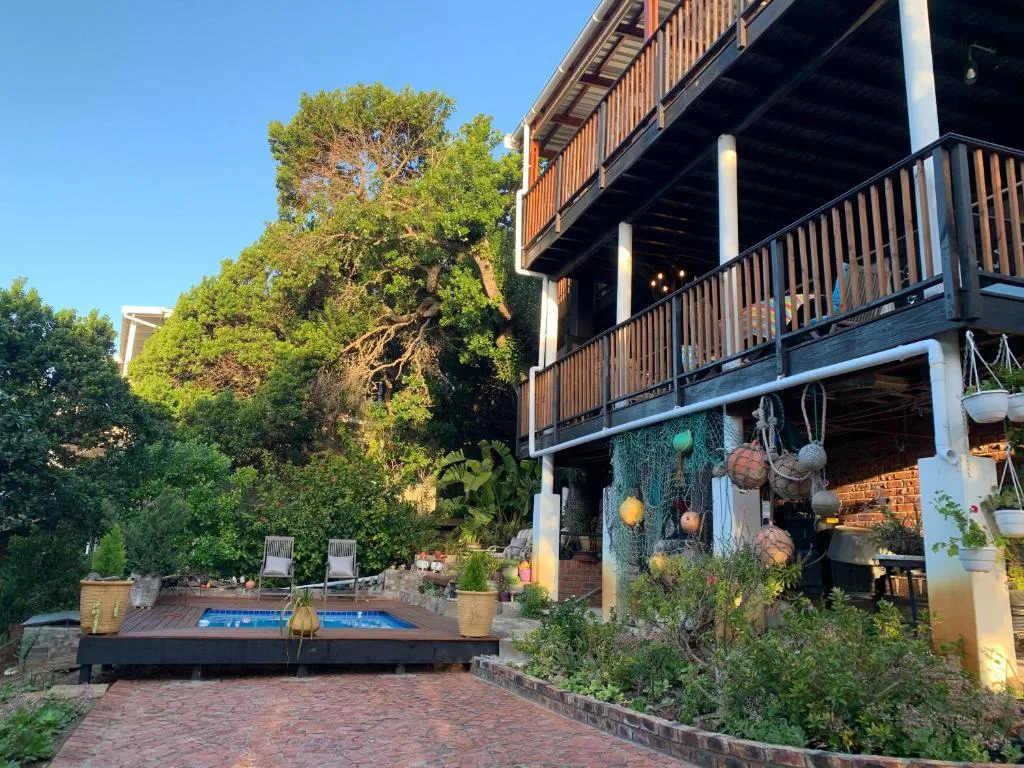 Modern multi-level accommodation with wooden decks, mature trees, and courtyard garden setting