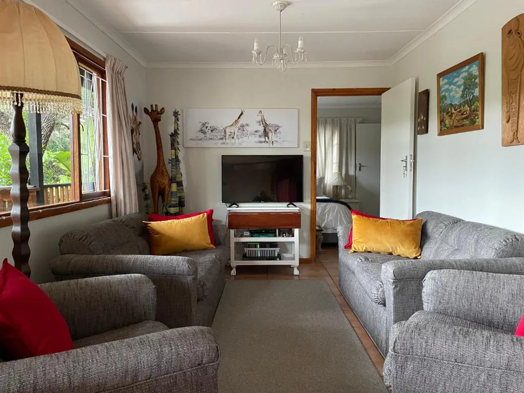 Spacious lounge with gray sofas, TV, African art, and bright accent pillows