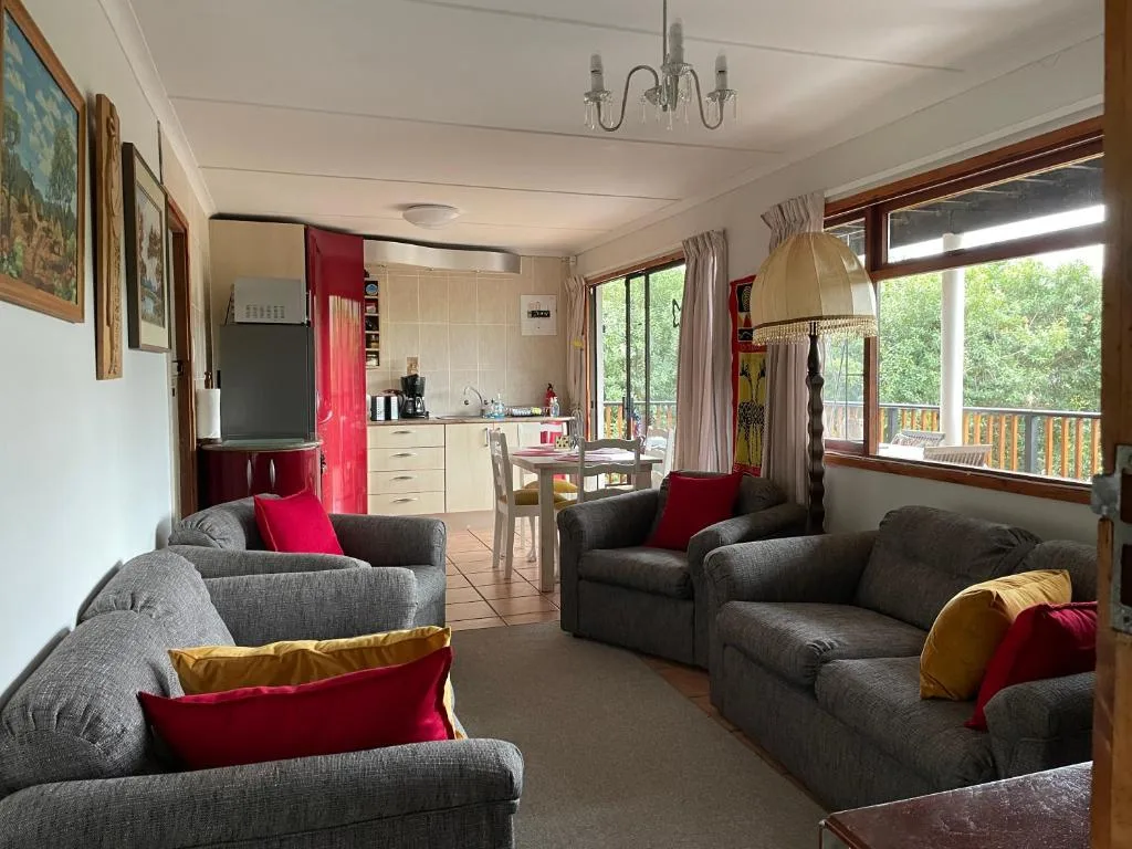 Open-plan lounge with gray sofas, red accents, and kitchen visible beyond