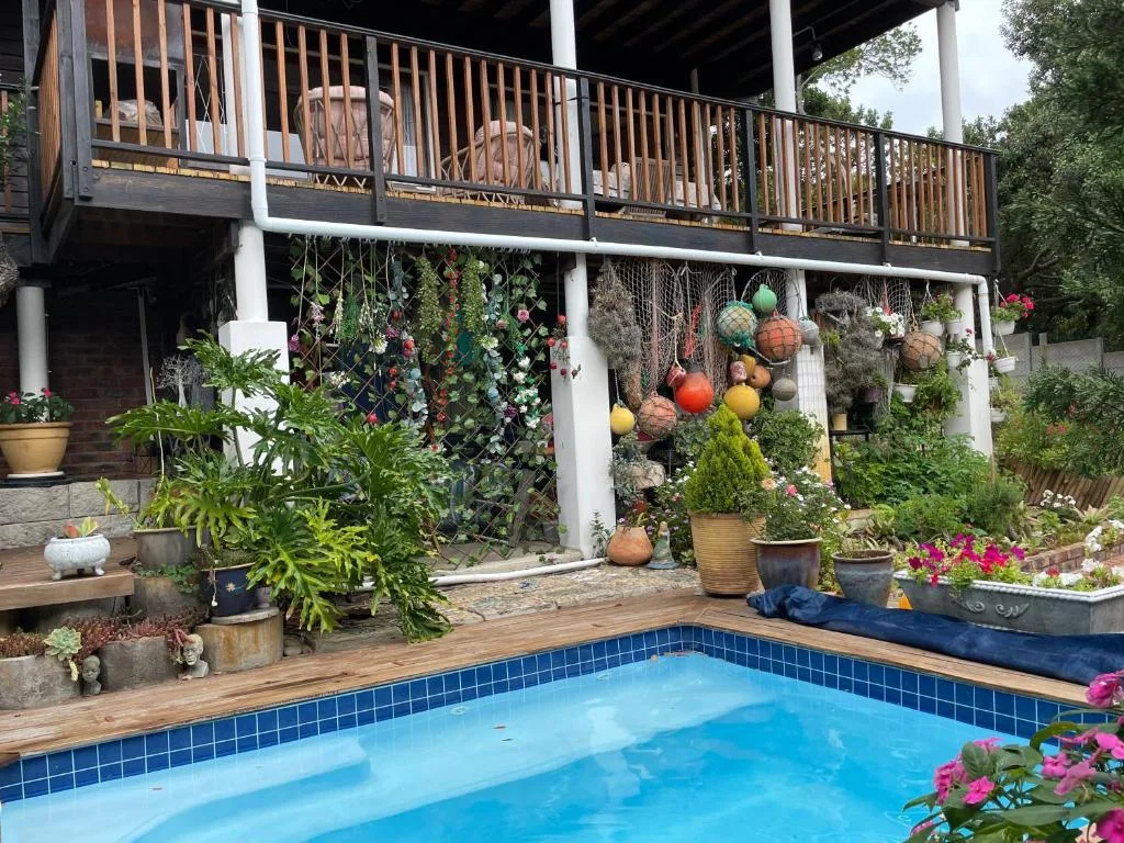 Sparkling blue pool with wooden deck, lush garden, and stylish house backdrop