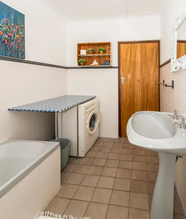 Bathroom with bathtub, pedestal sink, washing machine, and wooden door