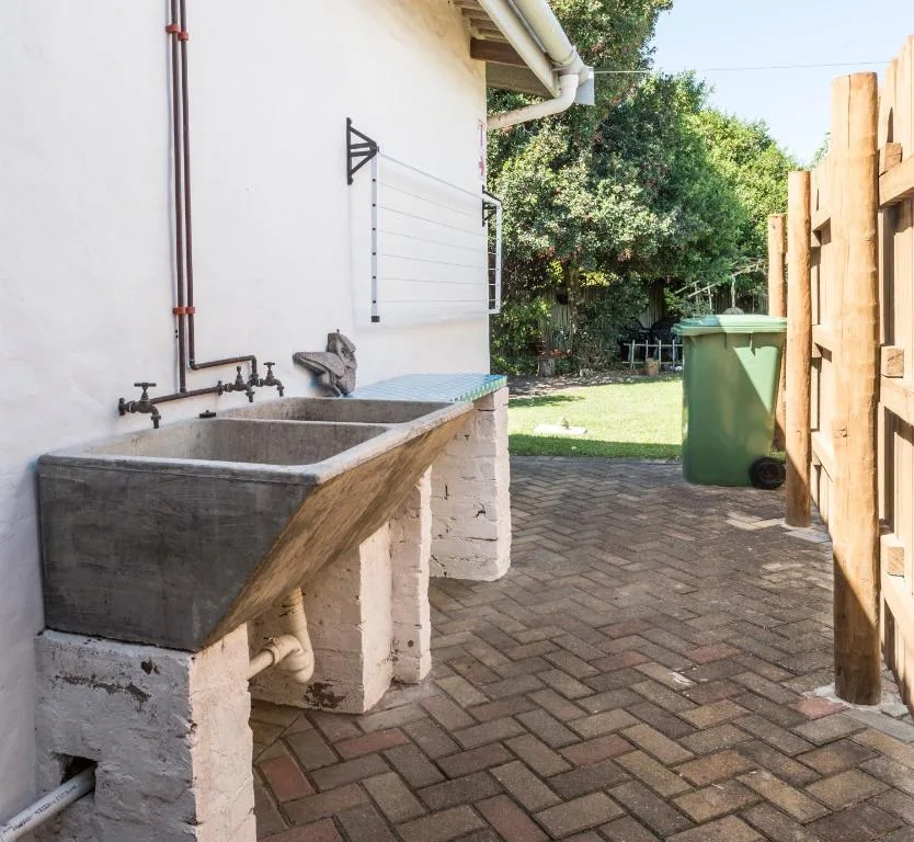 Rustic outdoor sink with two basins and vintage faucets on paved area
