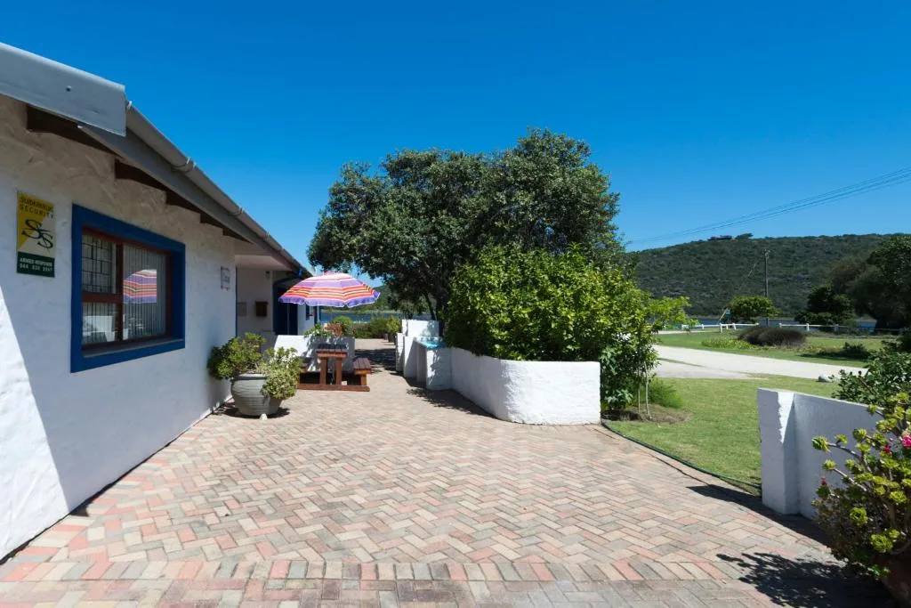 White cottage with blue trim and paved patio area overlooking green hills
