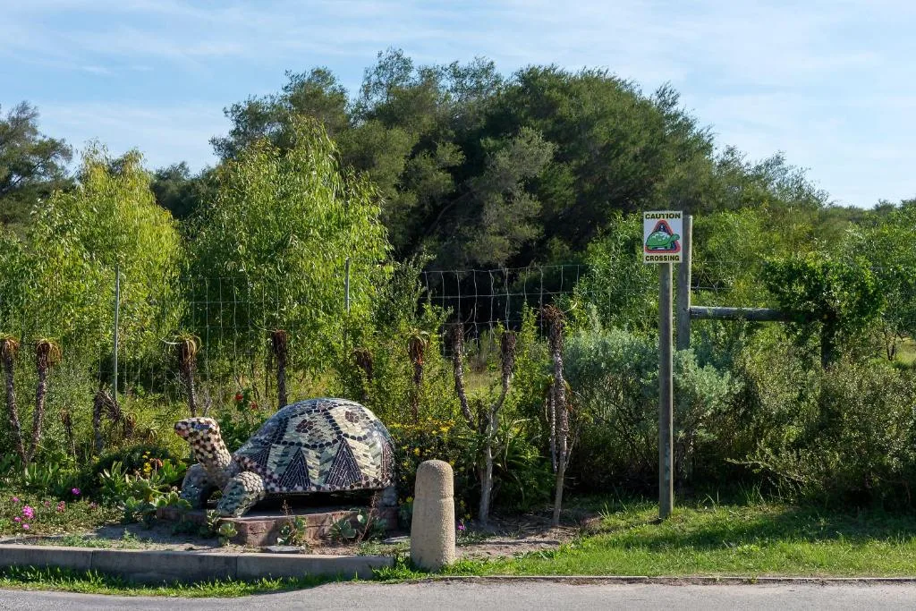 Garden entrance with decorative turtle sculpture and caution crossing sign