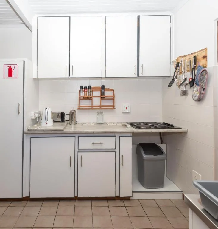 Compact kitchen with white cabinetry, cooktop, and storage organization