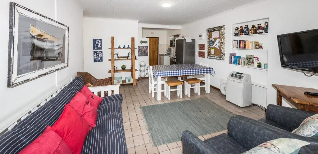 Open-plan lounge with striped sofa, red cushions, and wall-mounted TV
