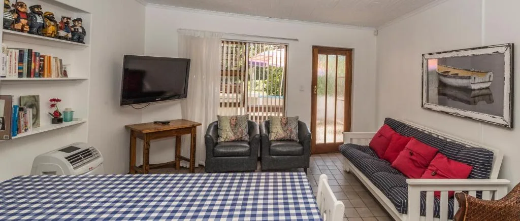 Open-plan lounge with TV, leather armchairs, and red cushioned seating area